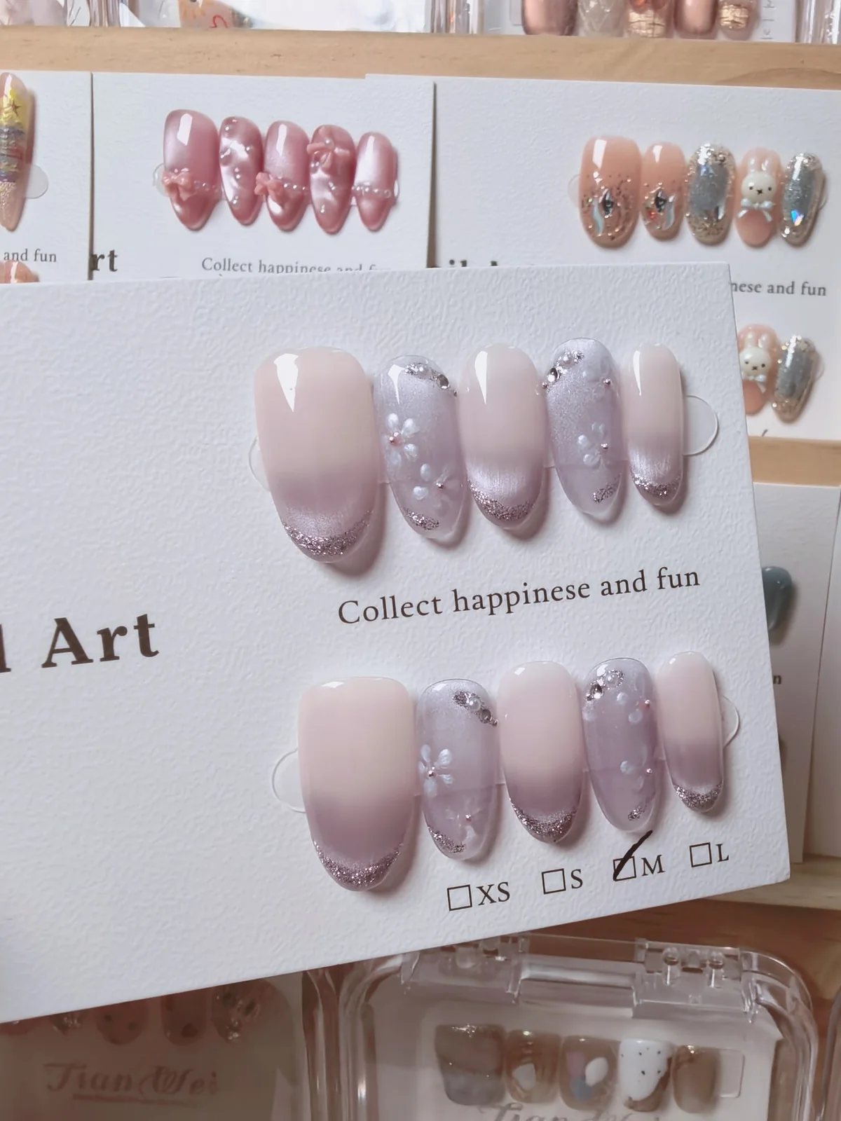 Hand-painted nude pink press-on nails with silver glitter French tips and floral details