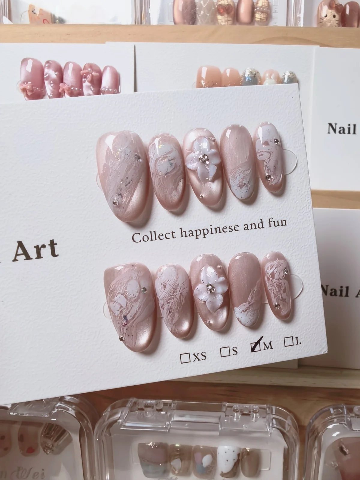Hand-painted nude pink press-on nails with white marble lines, flower decoration and crystals