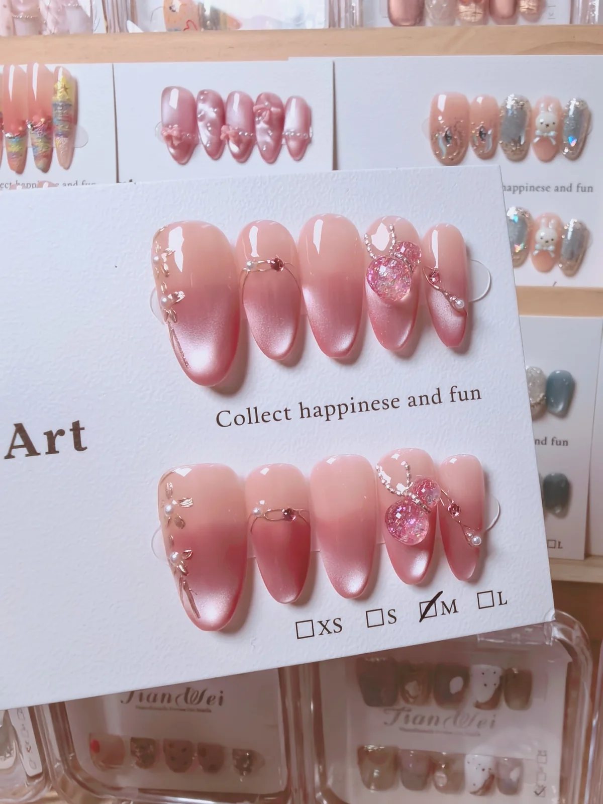 Handmade pink ombre press-on nails with metallic accents and decorative charms
