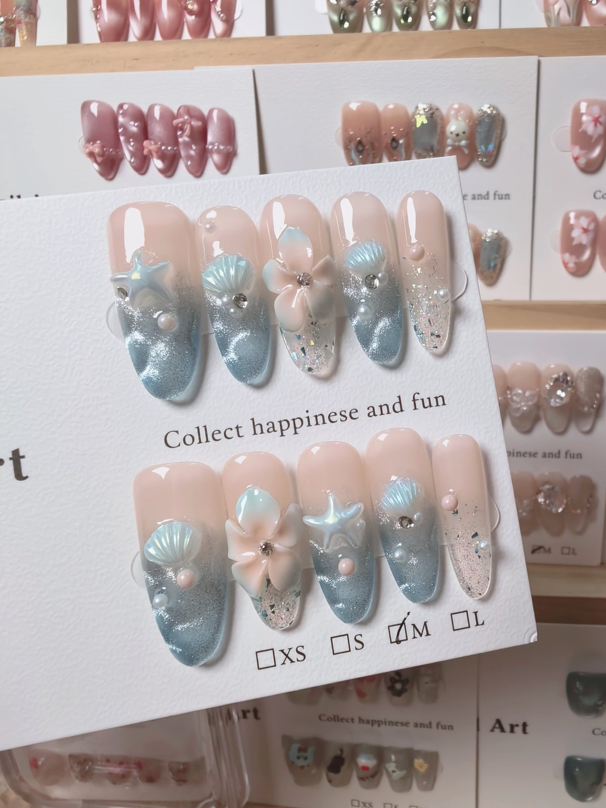 Handmade blue and nude press-on nails with shells, starfish, flower, pearls and glitter