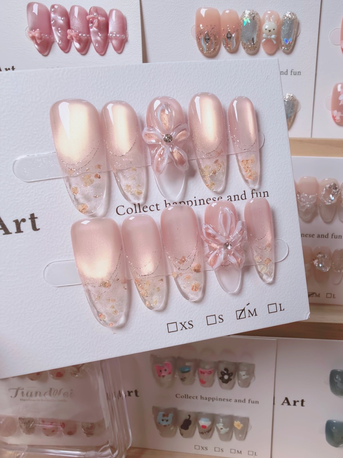 Handmade blush pink press-on nails with translucent flower, gold foil and French details